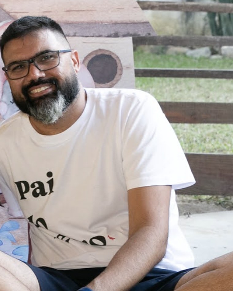 Rafael França smiling, sitting on the floor in a white T-shirt